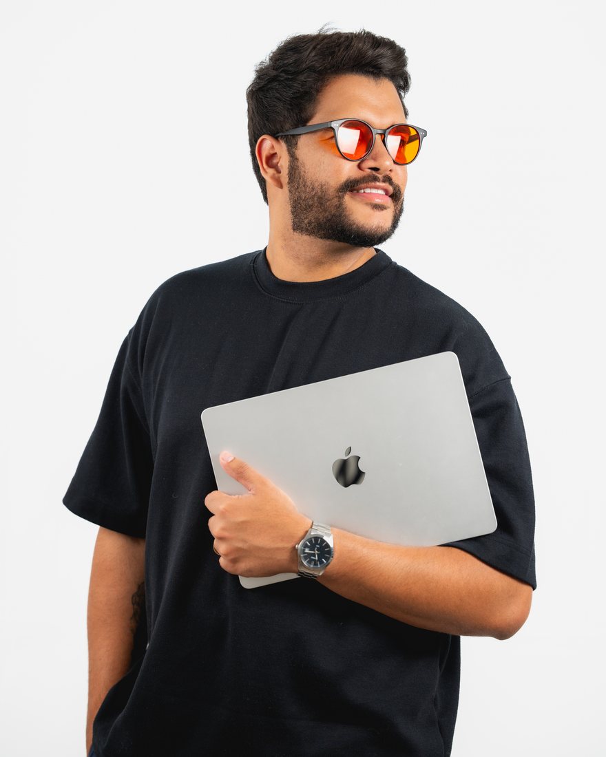 Retrato de estúdio de um homem segurando um notebook junto ao corpo